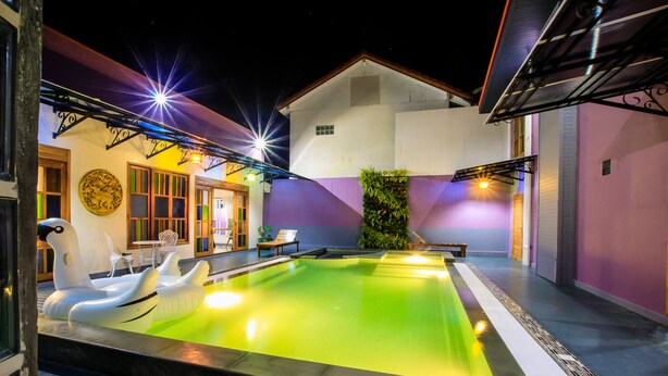 An indoor swimming pool with inflatable loungers, a wooden deck, and a purple wall. - Amethyst Boutique Hotel Fisherman's Village (Koh Samui)