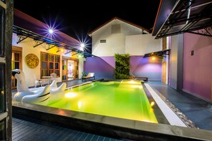 An indoor swimming pool with inflatable loungers, a wooden deck, and a purple wall. - Amethyst Boutique Hotel Fisherman's Village (Koh Samui)