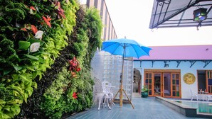 A rooftop terrace with a blue umbrella, white chairs, and a vertical garden. - Amethyst Boutique Hotel Fisherman's Village (Koh Samui)