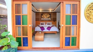 A bedroom with a bed centered in a wooden-framed room, a small bench, and a potted plant. - Amethyst Boutique Hotel Fisherman's Village (Koh Samui)