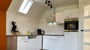 A kitchen with white cabinets, a coffee maker, a kettle, and a clock on the counter.