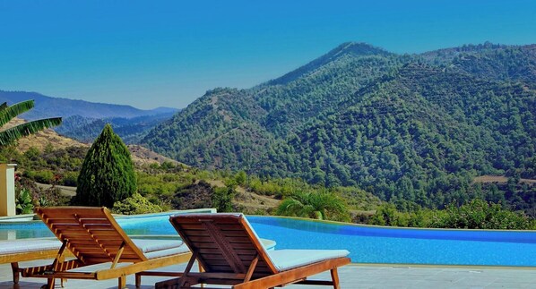 Ein Poolbereich mit Liegestühlen und Blick auf eine Berglandschaft.