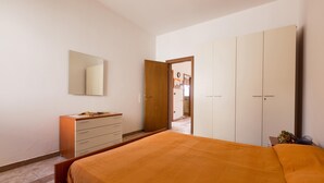 Een slaapkamer met een bed, een kapstok, een spiegel en een kledingkast.