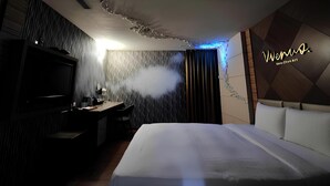 A modern hotel room with a large bed, a flat-screen TV, a desk with a chair, and a decorative wall with a logo. - Huaxiang Hotel - Zuoying (Kaohsiung)