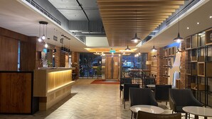 A modern interior with a reception desk, seating area, and bookshelves. - Huaxiang Hotel - Zuoying (Kaohsiung)