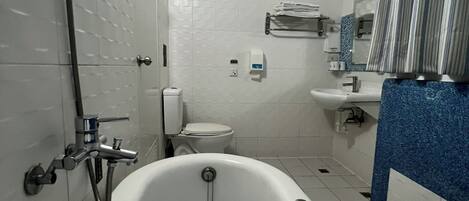 Un baño con bañera independiente, inodoro, lavamanos y ducha.