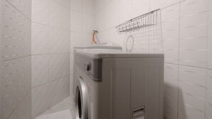 A compact laundry area with a washing machine and a drying rack. - Huaxiang Hotel - Zuoying (Kaohsiung)