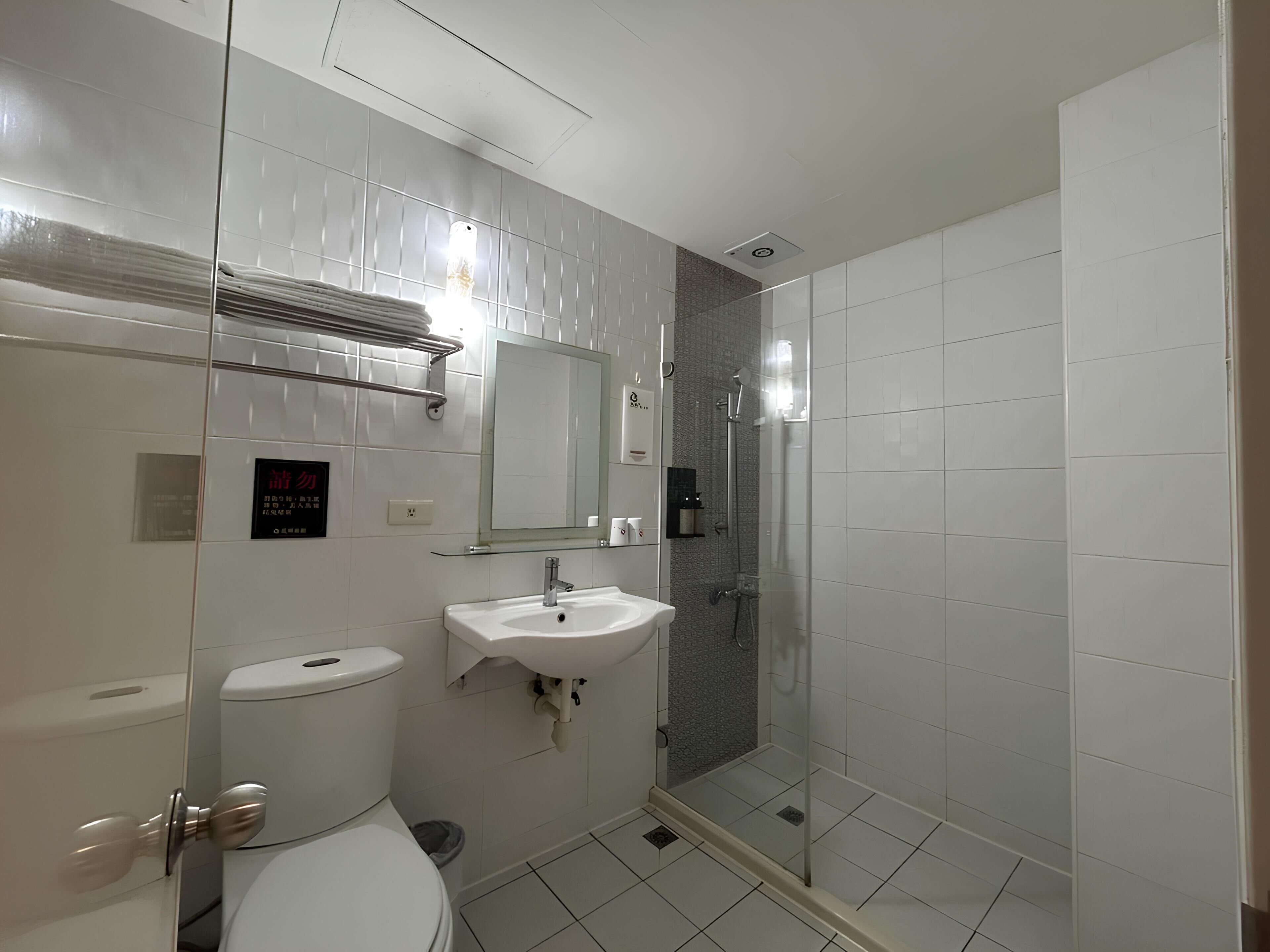 A modern bathroom with a toilet, sink, and glass-enclosed shower.