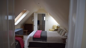 A bedroom with a bed, a desk, a chair, and a wardrobe.