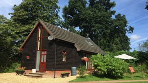 A wooden cabin with a red door, a satellite dish, and flower boxes.