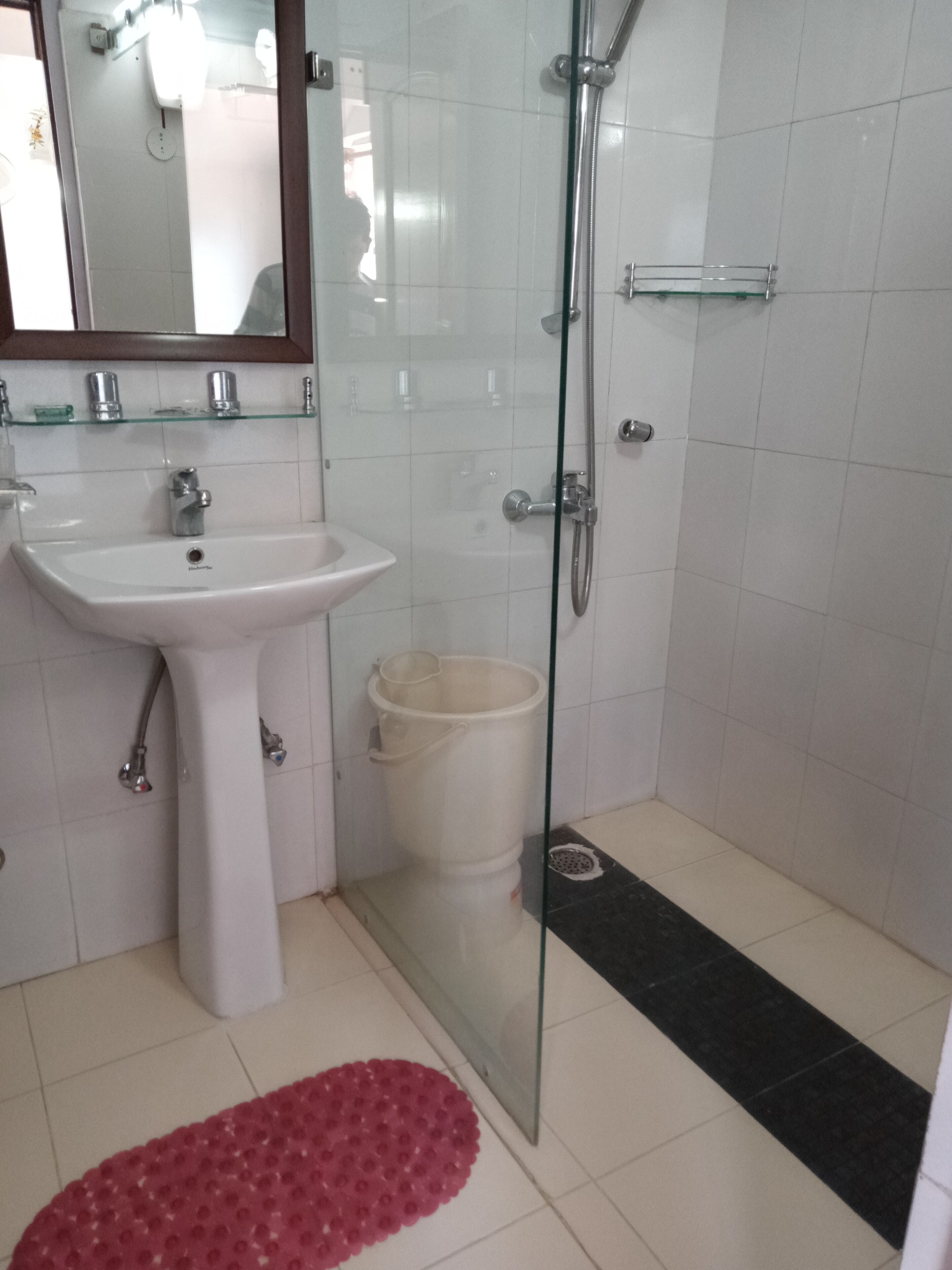 A bathroom with a white sink, a glass shower enclosure, and a white toilet.