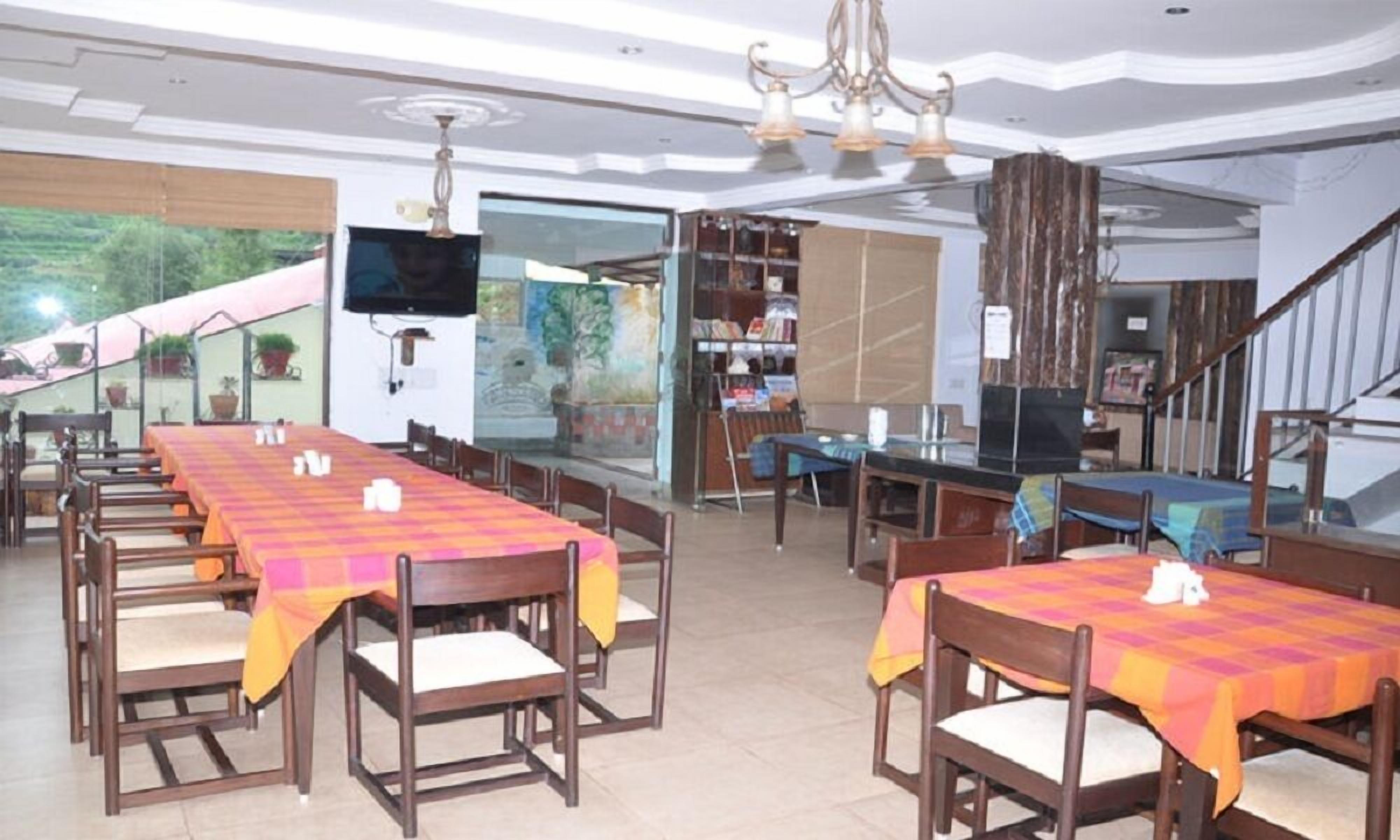 A dining area with tables and chairs, a television, and a bookshelf.