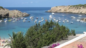 A coastal marina with various boats docked, surrounded by rocky terrain and clear skies. - Charming villa with sea view- next to the beach-Ideal for couples and families (Cala -Vadella)