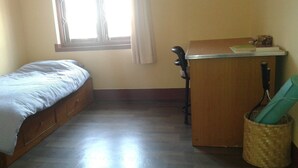 Una stanza piccola con un letto singolo, una scrivania e una finestra.