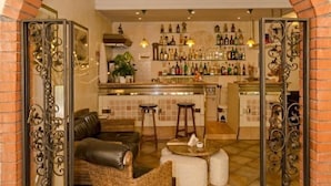 A cozy interior with a brick archway leading to a bar area, featuring a leather sofa, wicker chairs, and a tiled floor. - Hotel Euromar (Massa)