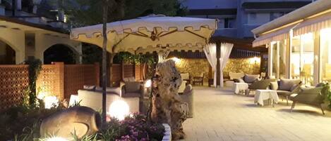 An outdoor patio area with stone planters, a large umbrella, and outdoor seating.