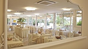 A restaurant with multiple tables set for dining, large windows allowing natural light, and a view of the outdoors. - Hotel Euromar (Massa)