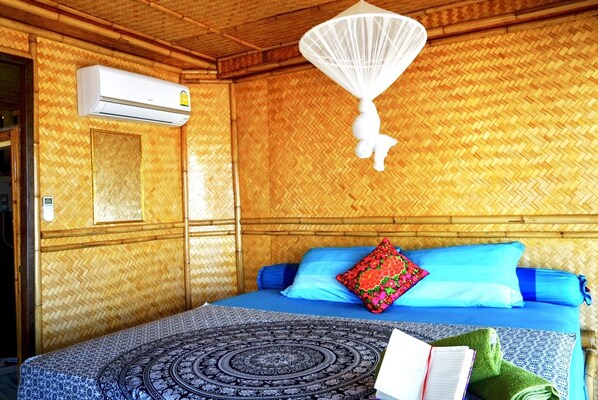 Una habitación con una cama, mosquitero, aire acondicionado y un tapete estampado.