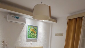A neatly arranged bedroom with a bed, bedside table, and an air conditioning unit. - CALLIOPE MAILLE STUDIOS & APARTMENTS (Kalymnos)