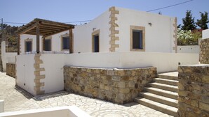 A white building with stone walls and a wooden pergola.