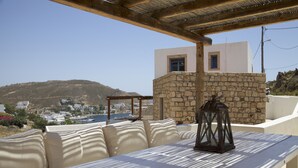 An outdoor seating area with a stone wall and a view of a hillside town.
