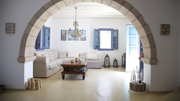 A living room with a stone archway, a sofa, a coffee table, and a chandelier.