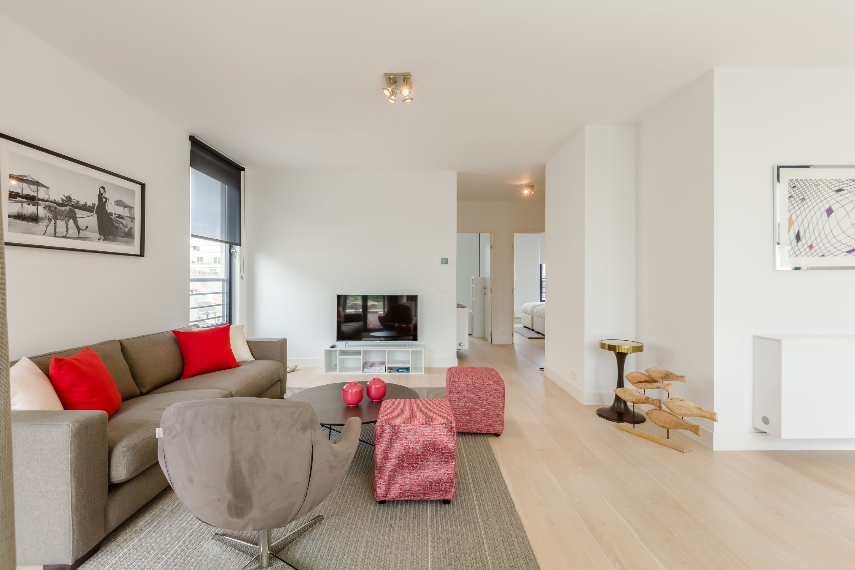 Una sala de estar moderna con un sofá, cojines rojos, una mesa de centro y un televisor.