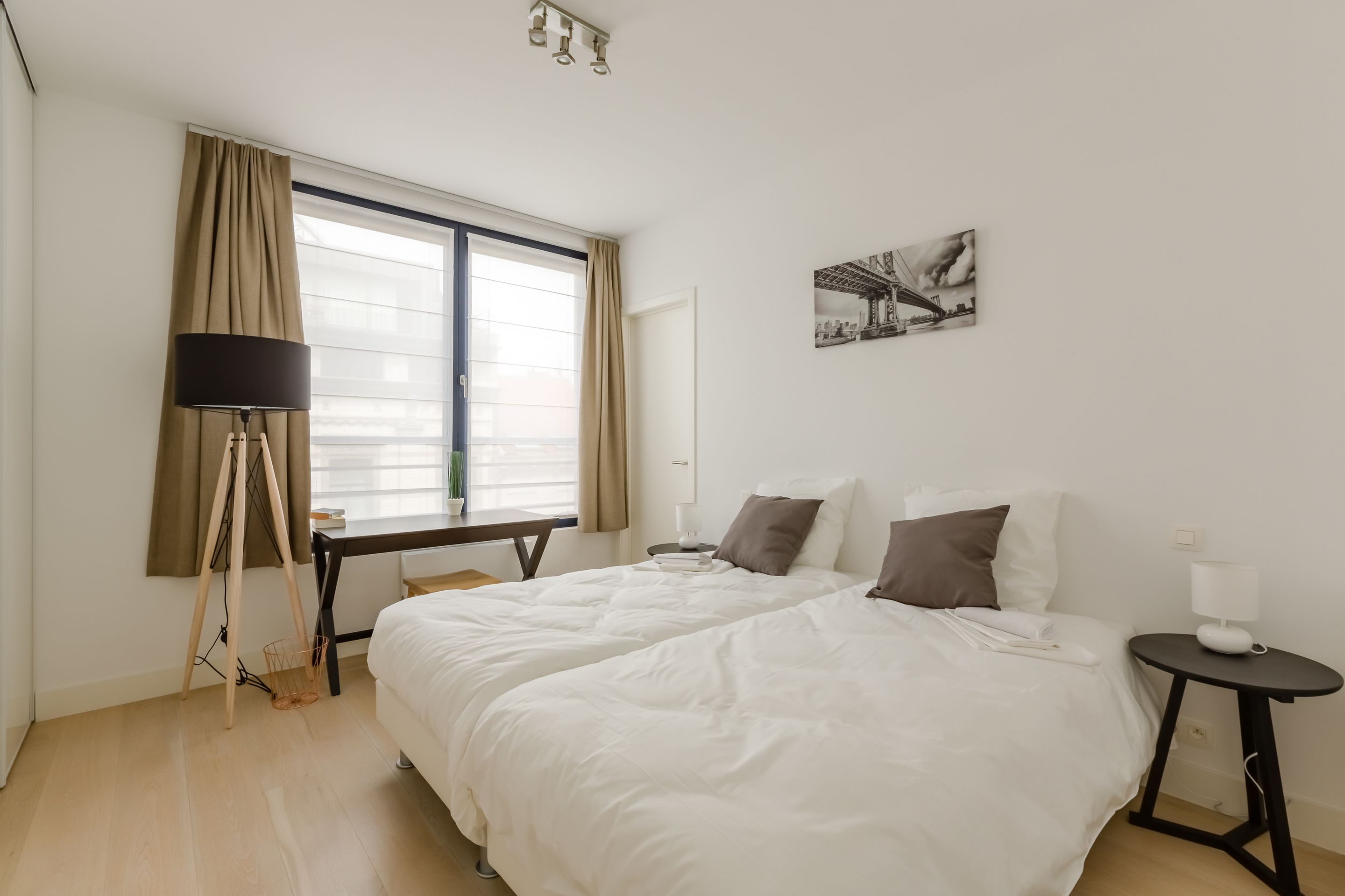 A hotel room with a large bed, a desk, a chair, a lamp, and a window with curtains.