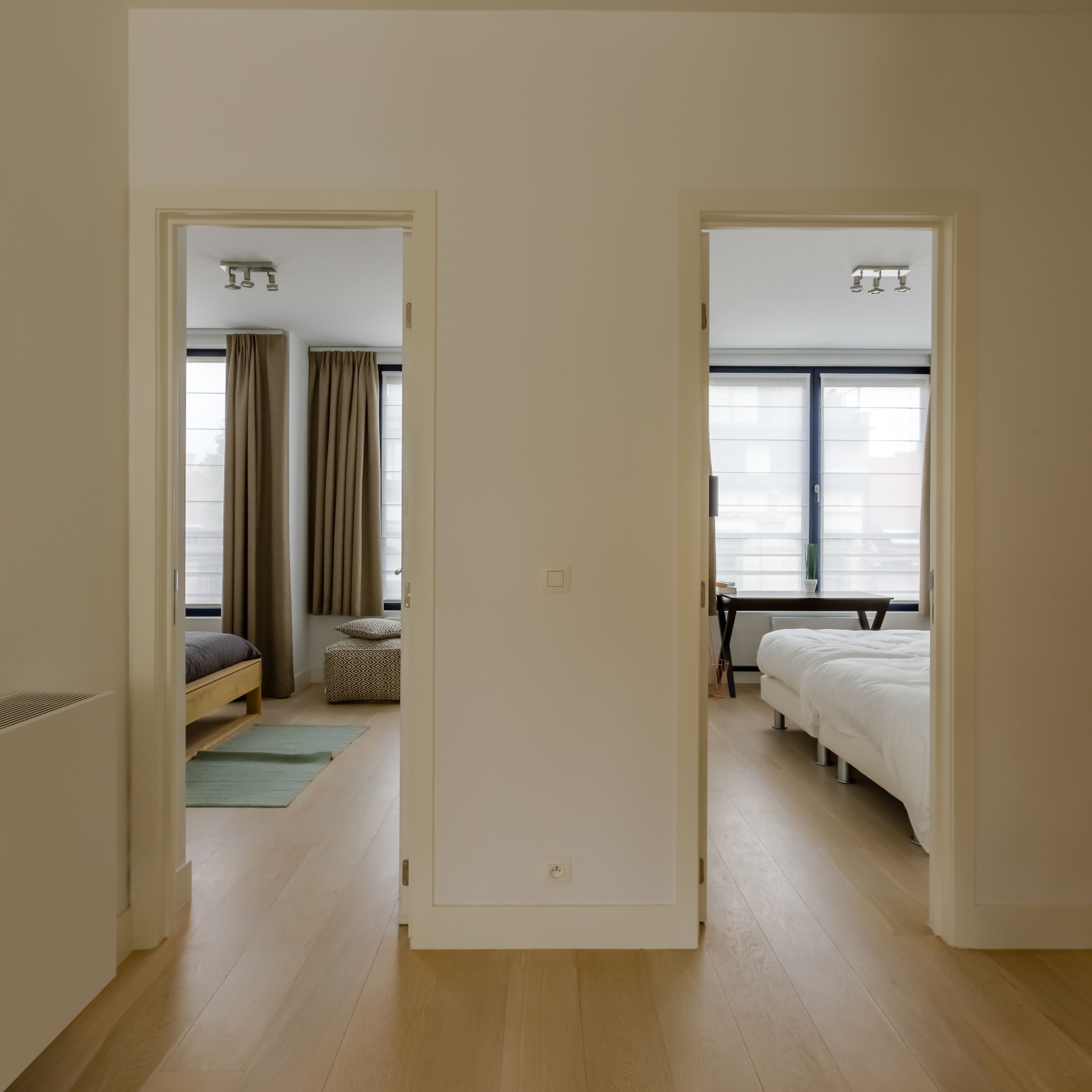 A hotel room with a bed, a desk, and a window with blinds.