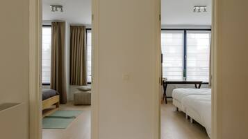 A hotel room with a bed, a desk, and a window with blinds.