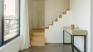 Un intérieur moderne avec un escalier, une fenêtre avec des rideaux et une petite table.