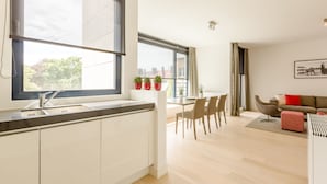 Une cuisine moderne avec une grande fenêtre, un coin repas avec des chaises et un canapé avec des coussins.