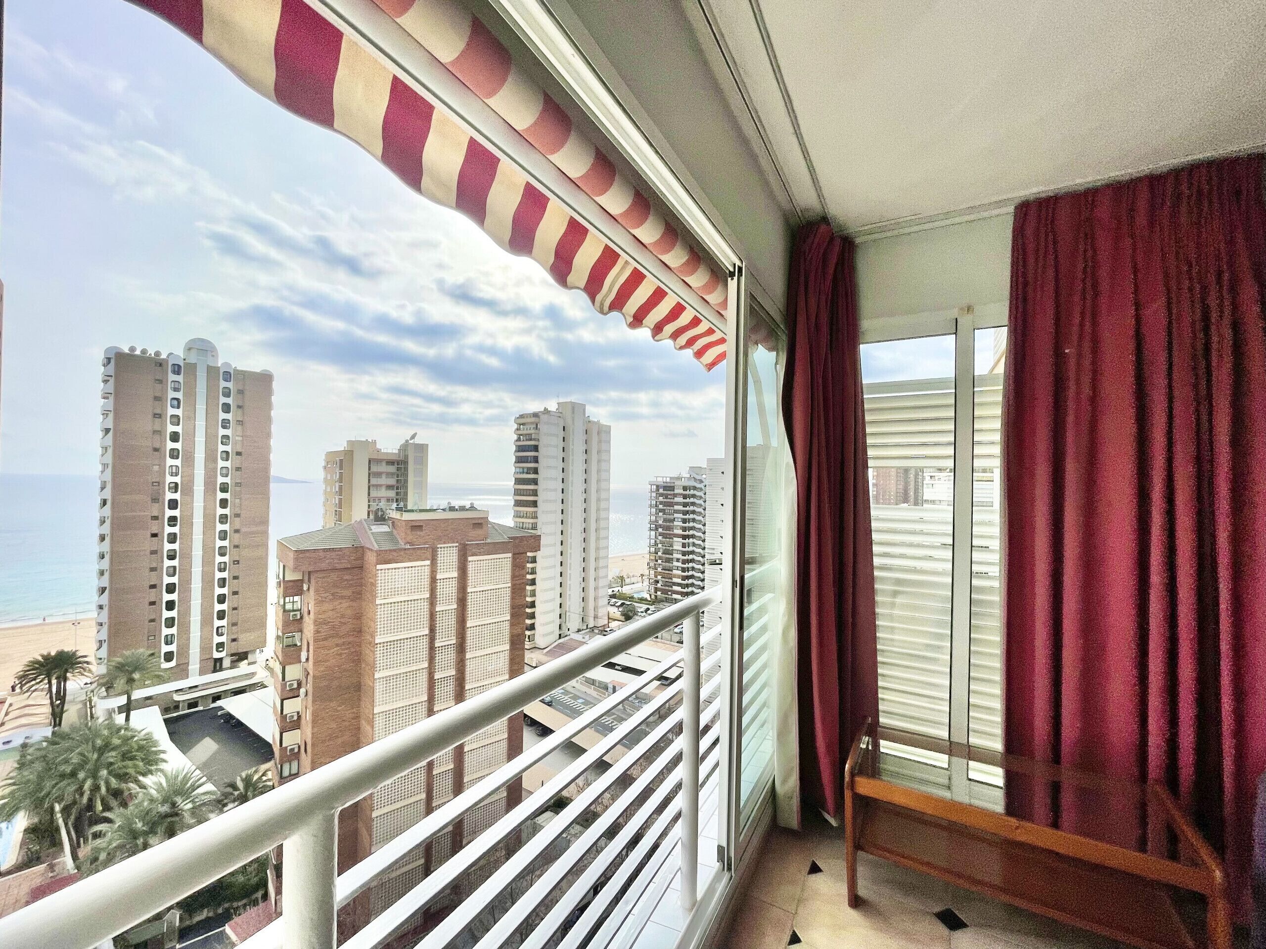 A balcony with a view of tall buildings and a beach.