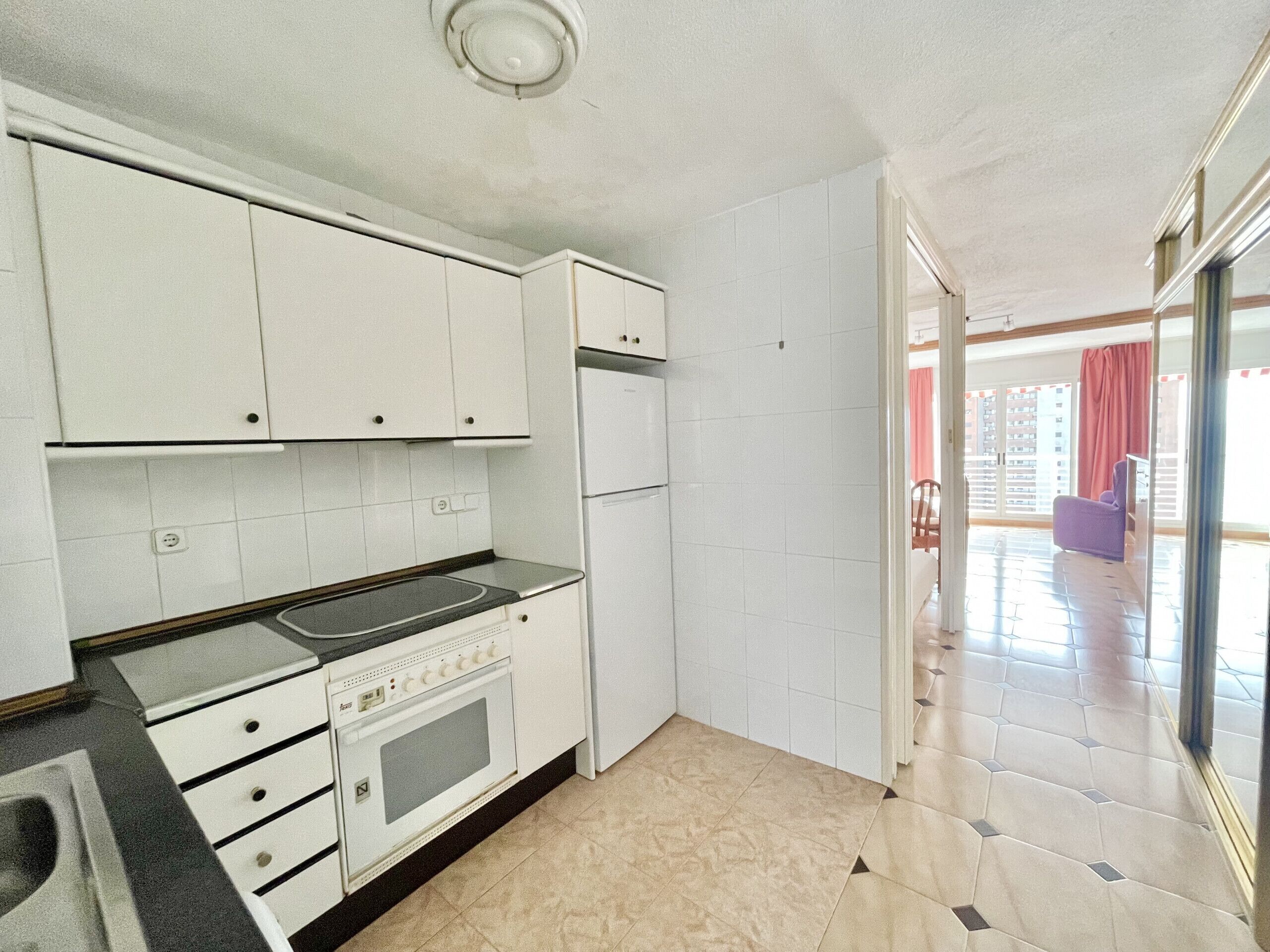 A kitchen with white cabinets, a stove, and a refrigerator.