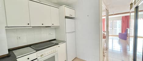 A kitchen with white cabinets, a stove, and a refrigerator.