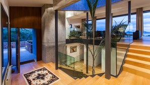 A modern interior with a glass staircase, wooden flooring, and a view of the outdoors.
