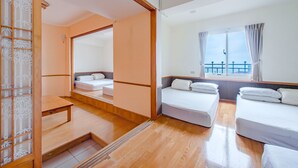 A hotel room with a wooden floor, two beds, a small table, and a sliding door with a bamboo pattern. - CF Kite Homestay (New Taipei City)