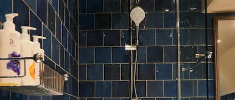 Un baño con bañera, ducha y estante con artículos de aseo.