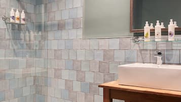 A modern bathroom with a glass shower enclosure, a wooden vanity, and a large mirror.