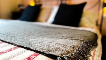 A bed with a patterned bedspread and a dark throw blanket.