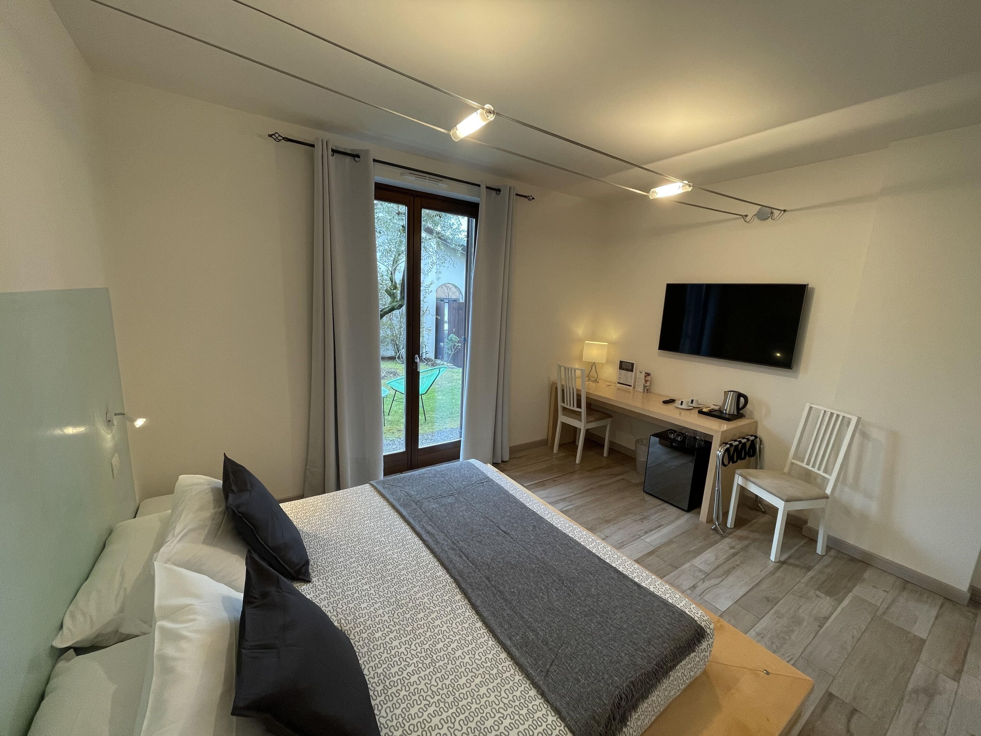 Ein modernes Hotelzimmer mit Bett, Schreibtisch, Stuhl, Fernseher und Blick ins Freie.