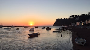A beach scene with boats, a sunset, and buildings along the shore. - Charming Beachside Cottage, just had cancelation ,avail now 22-31st Aug,7 d min (Shaldon)