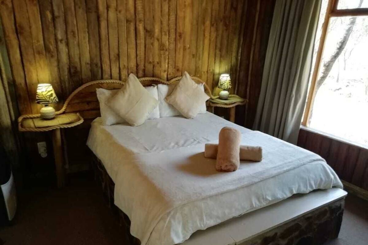 A bed with a white bedspread and pillows, a stone base, and two bedside tables with lamps.