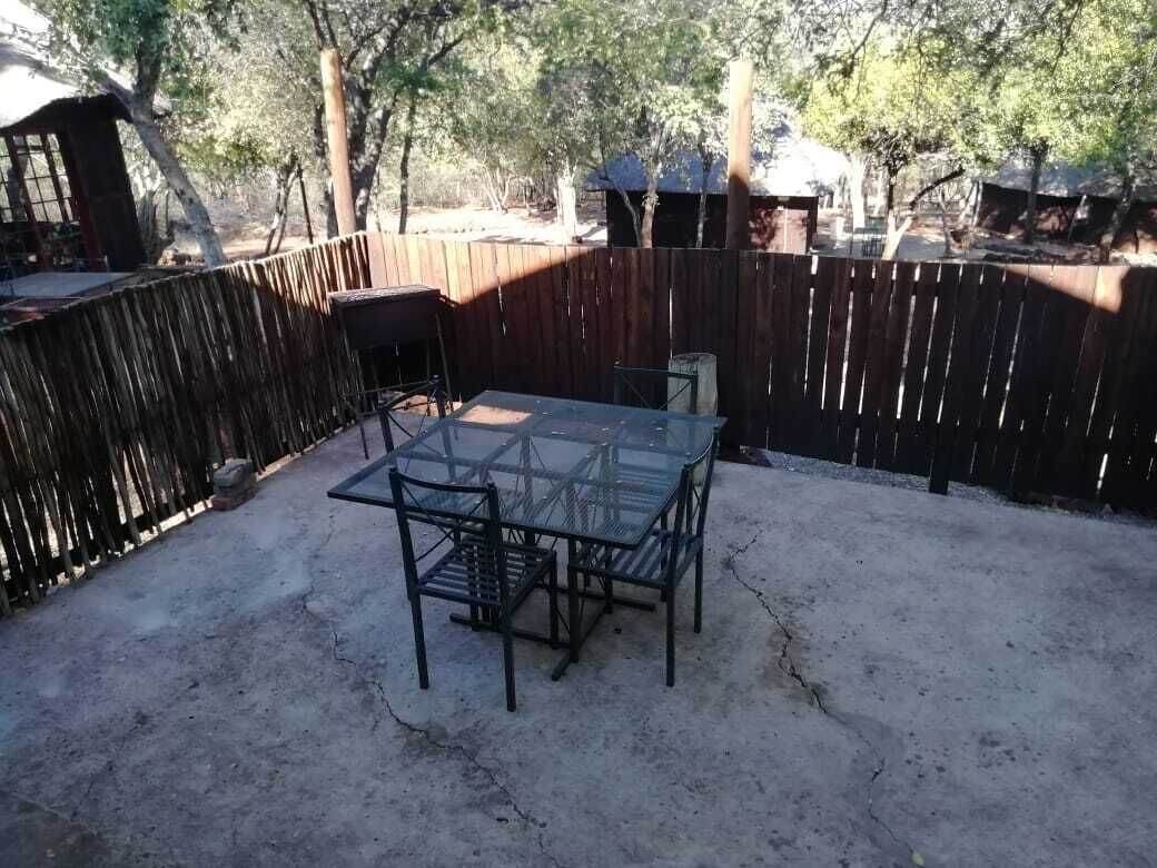 Un espace patio avec une table et des chaises en verre, entouré d’une clôture en bois.
