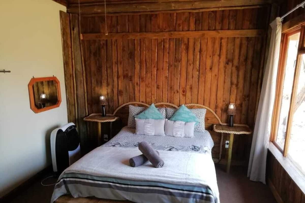 A wooden-paneled bedroom with a bed, two bedside tables, and a window.
