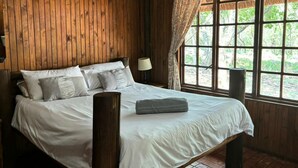 A wooden room with a bed, a window, and a lamp. - Thabankwe Bushveld Inn (Thabazimbi)