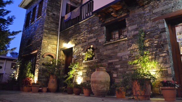 Un bâtiment en pierre doté d’un balcon et agrémenté de plantes en pot.