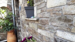 Un mur de pierre avec une plante en pot et un pot de fleurs.