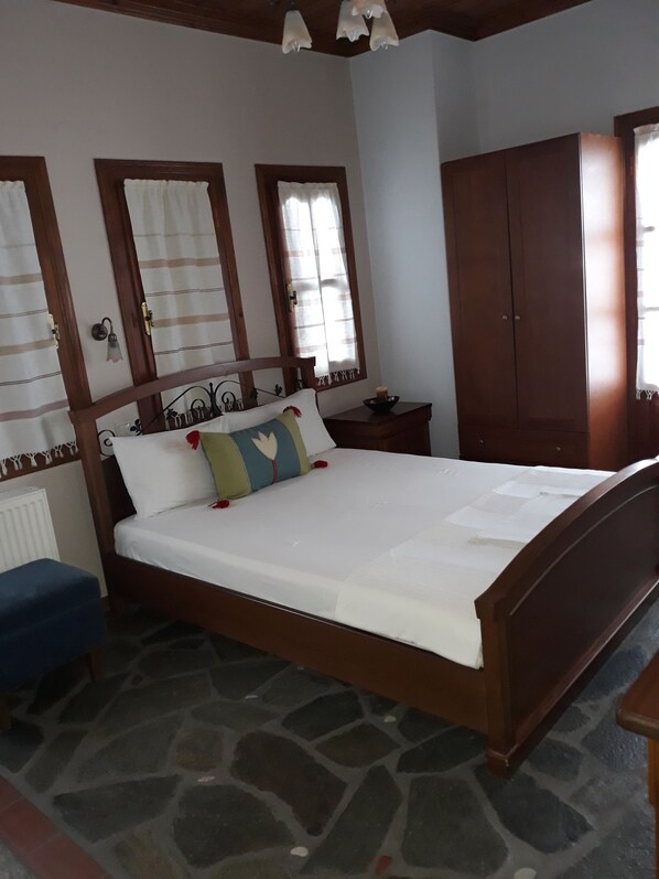 Un dormitorio con una cama de madera, una mesita de noche, un armario y una ventana con cortinas.
