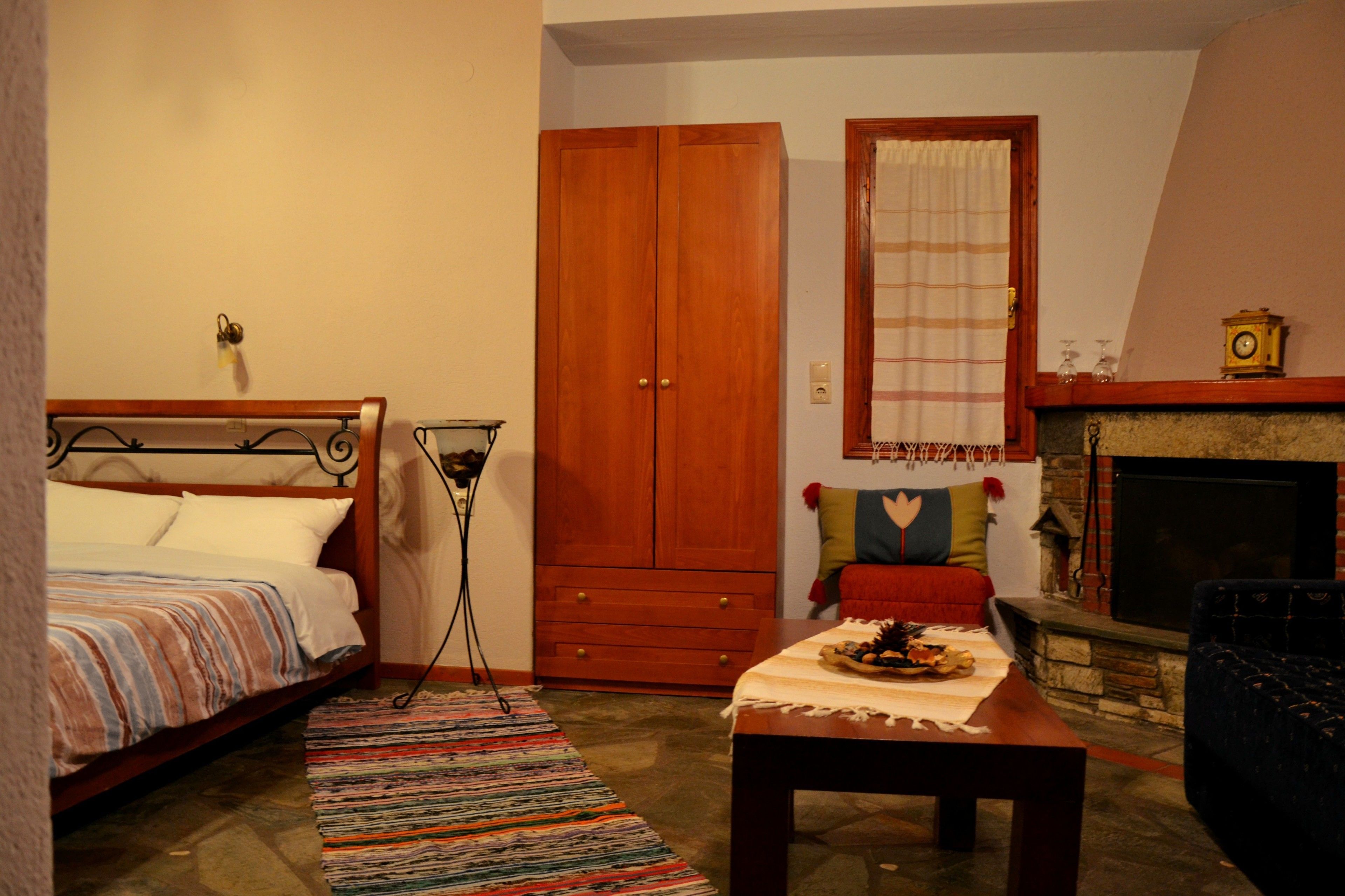 Une chambre à coucher avec un lit, une armoire en bois, une cheminée et une petite table recouverte d’une couverture.
